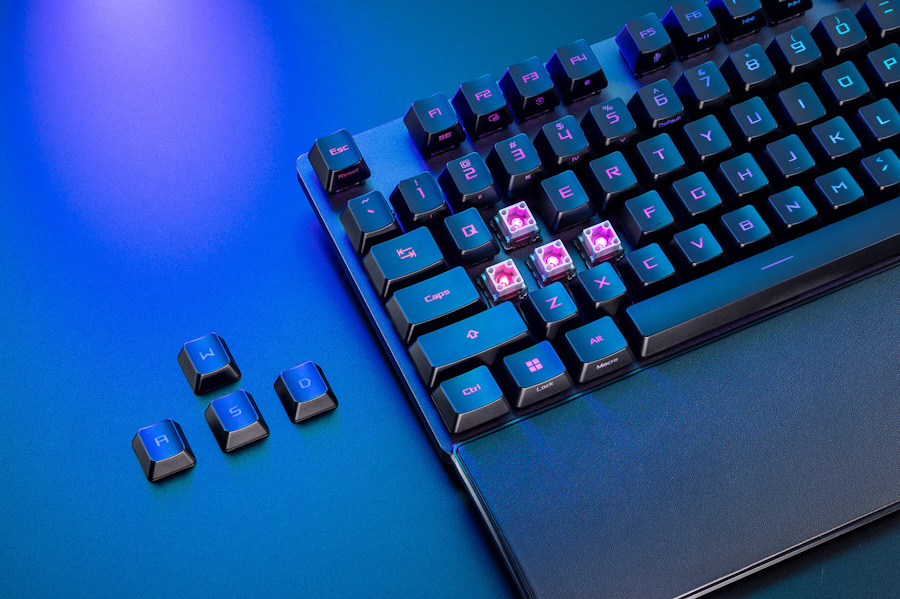 Close-up on the left area of ROG Strix Scope II RX on a table with some keycaps removed showing the ROG RX optical switches